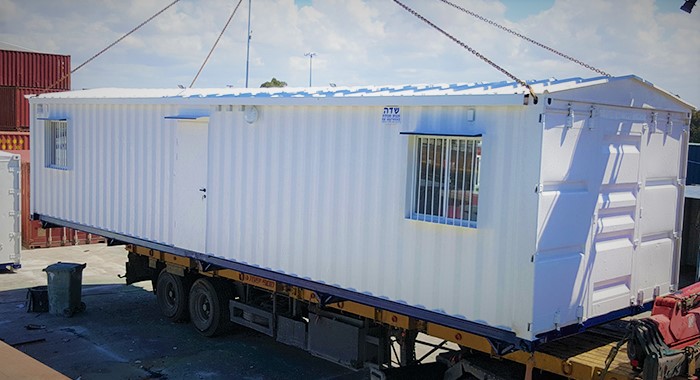 מכולה לבנה תלויה באוויר עם מנוף מייצגת מכולות מטעם חברת SADE מכולות ומבנים יבילים
